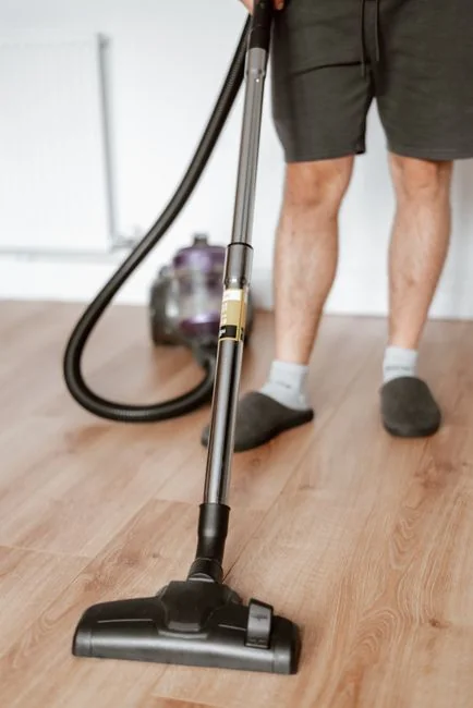 An adult male cleaning a glass window indoors, focusing on household chores and cleanliness.